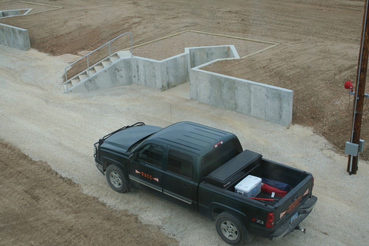 A pickup truck parked next to a concrete stairway leading to a lower level of a construction site.