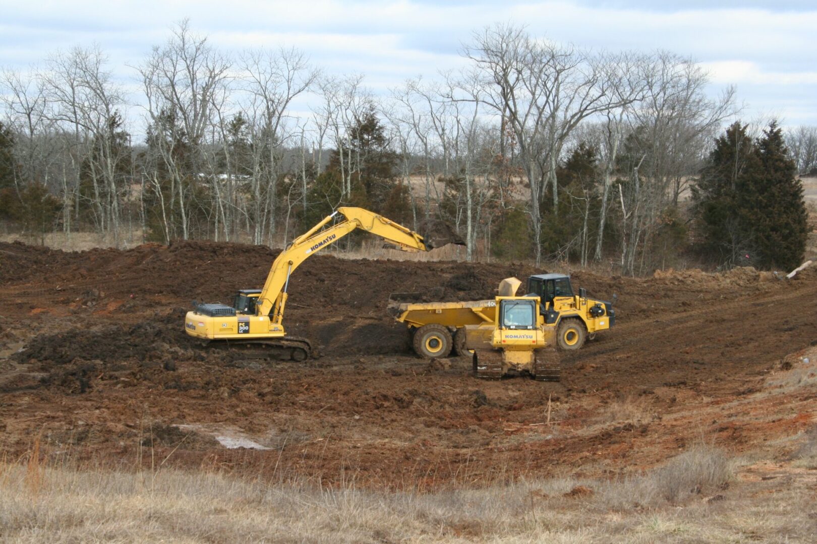 An excavator loading soil into a dump truck at a construction site.