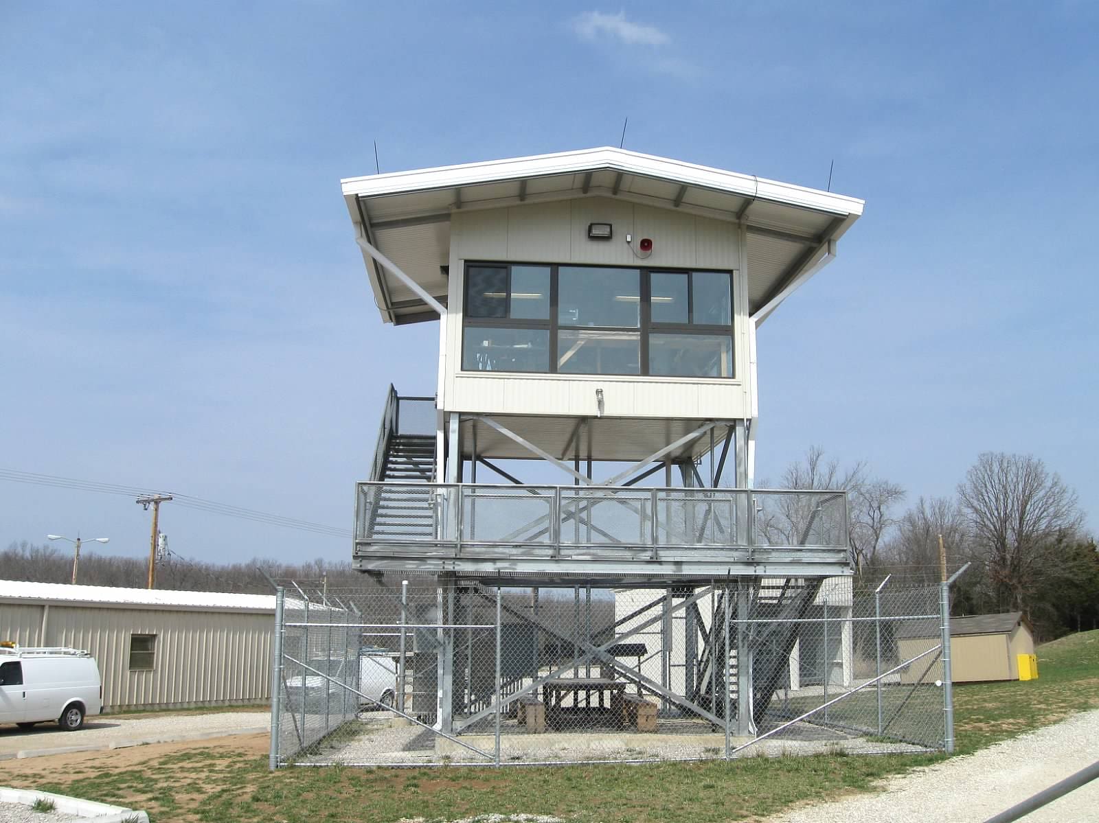Elevated control tower with metal staircase on a clear day.