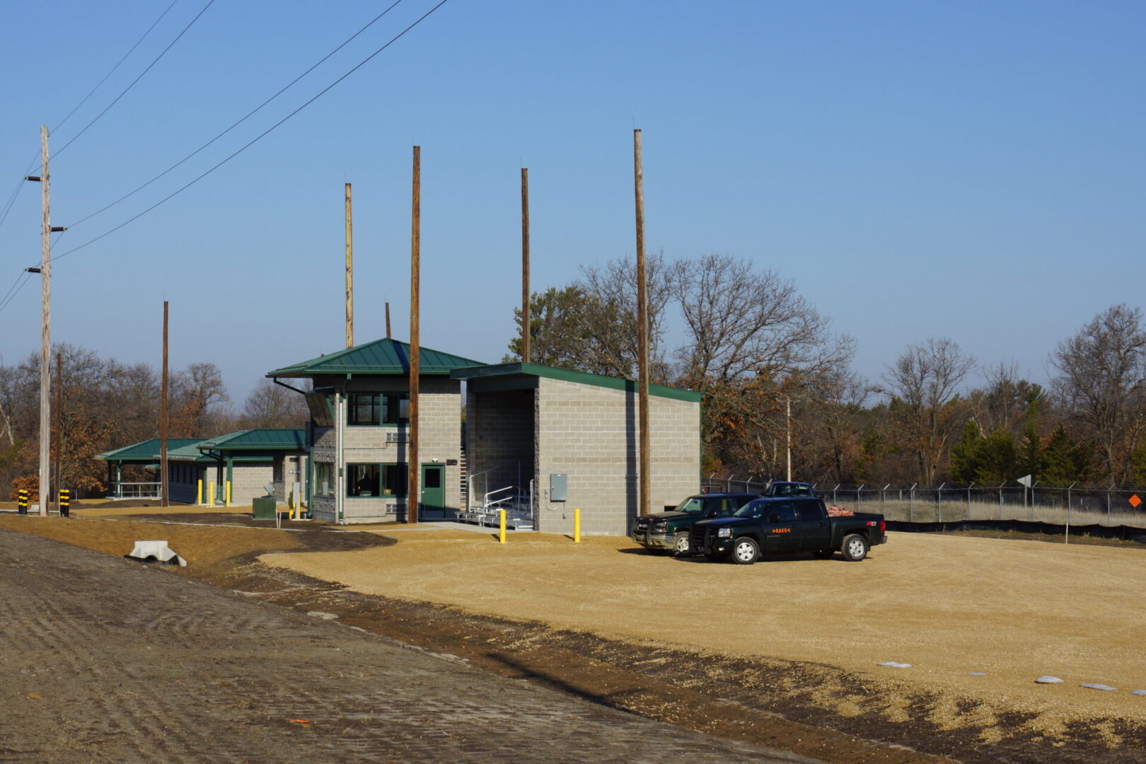 An industrial facility with a fenced perimeter and a truck parked outside.