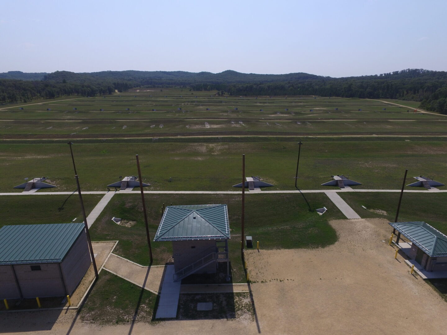 Aerial view of a wastewater treatment facility with several tanks and structures, surrounded by a grassy area.