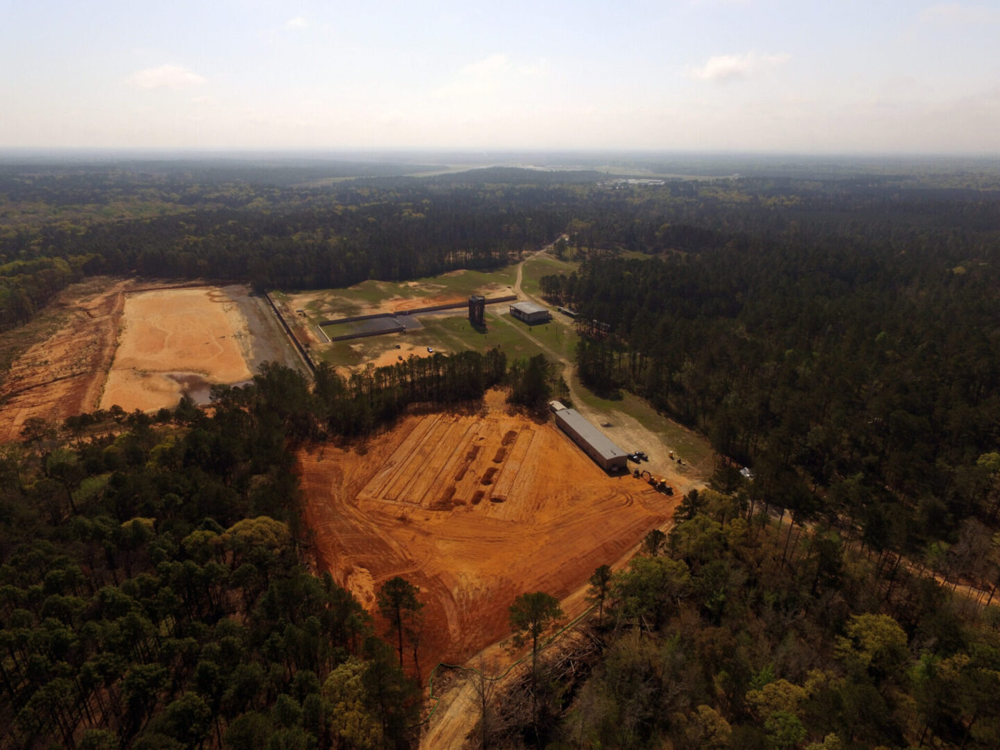 Aerial view of a large construction site with cleared land surrounded by a forest.