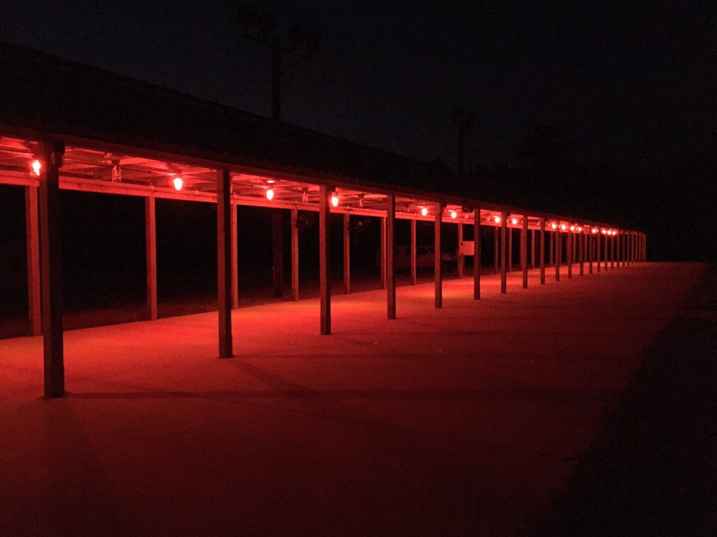 A row of outdoor structures illuminated by red lights at night.