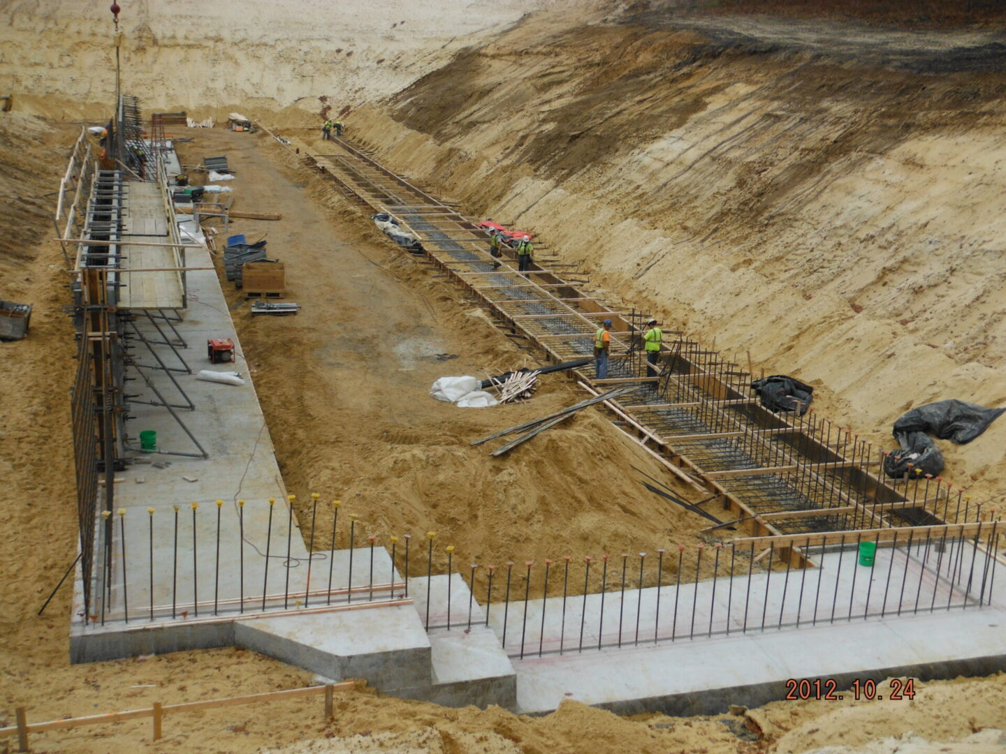 Construction workers laying the foundation at a large excavation site.