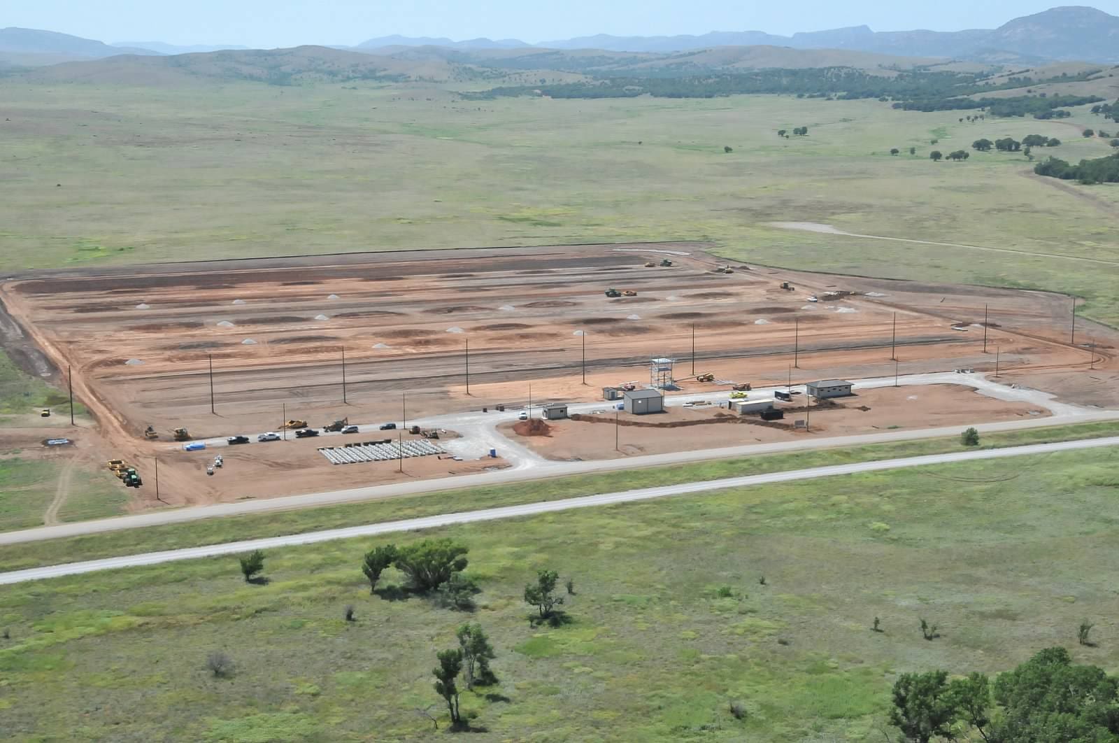 An aerial view of a large industrial site under construction with equipment and vehicles scattered across the area.