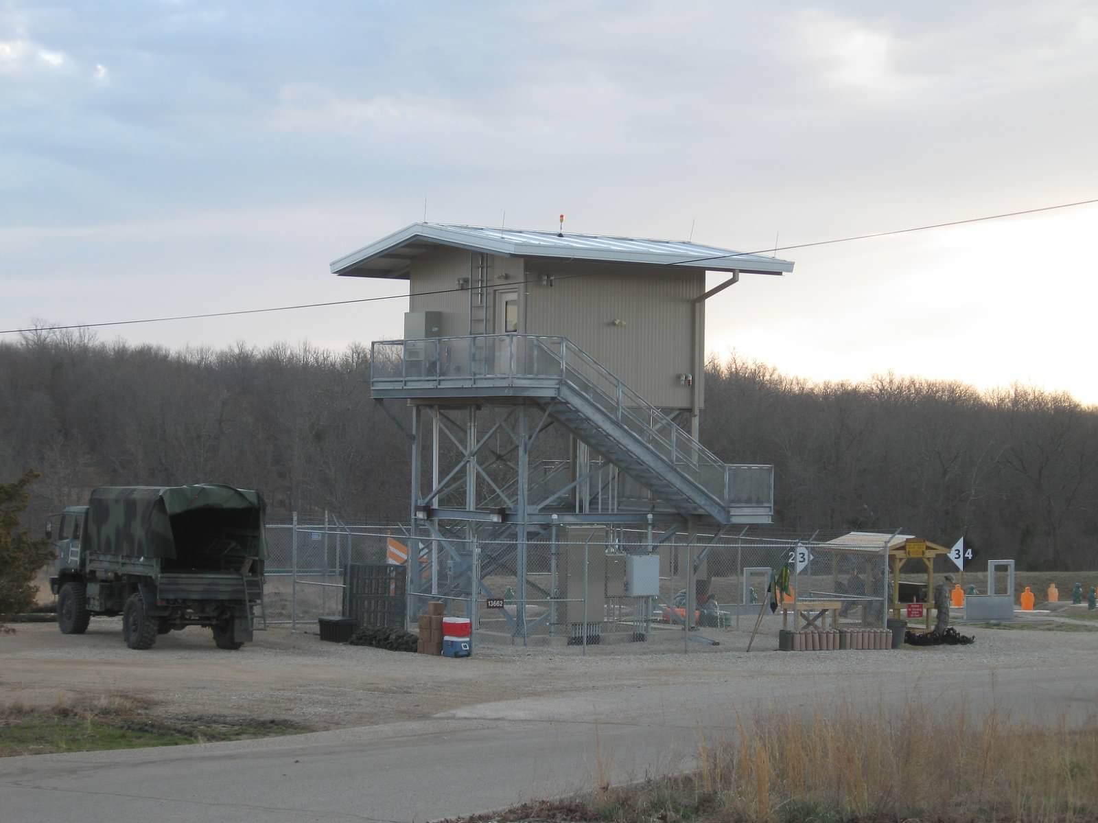 A military checkpoint with a guard tower and a parked truck.