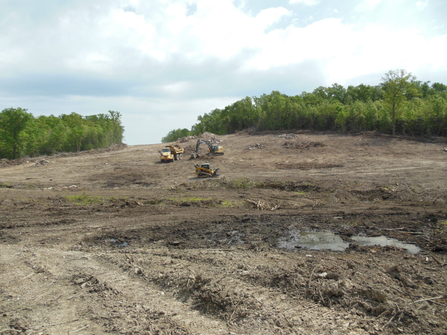 Land clearing in progress with heavy machinery on a partly deforested terrain.